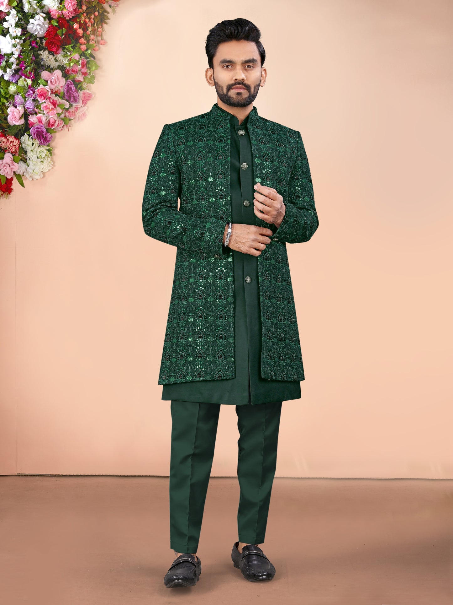 Man wearing a green traditional outfit with a floral background