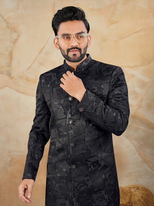 Man wearing a black traditional outfit against a beige background