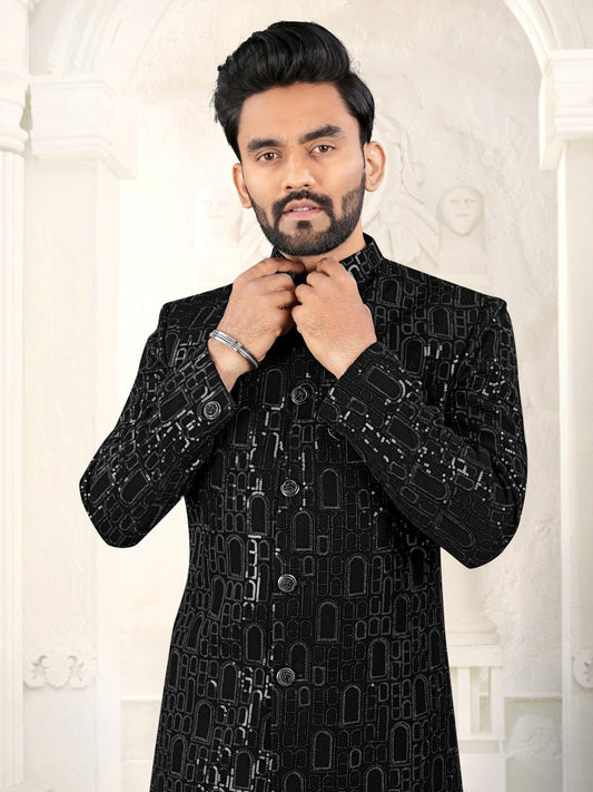 Man wearing a black embroidered sherwani against a white background