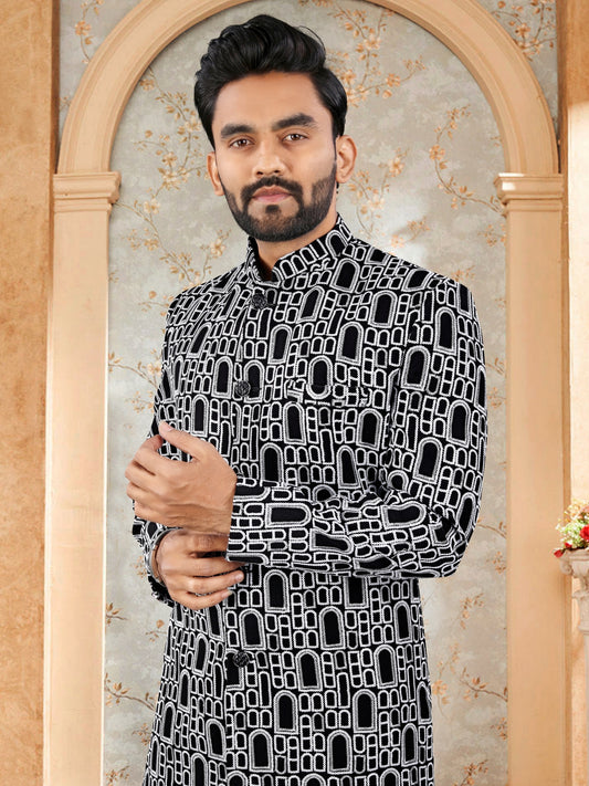 Man wearing a black and white patterned shirt in front of an ornate mirror.