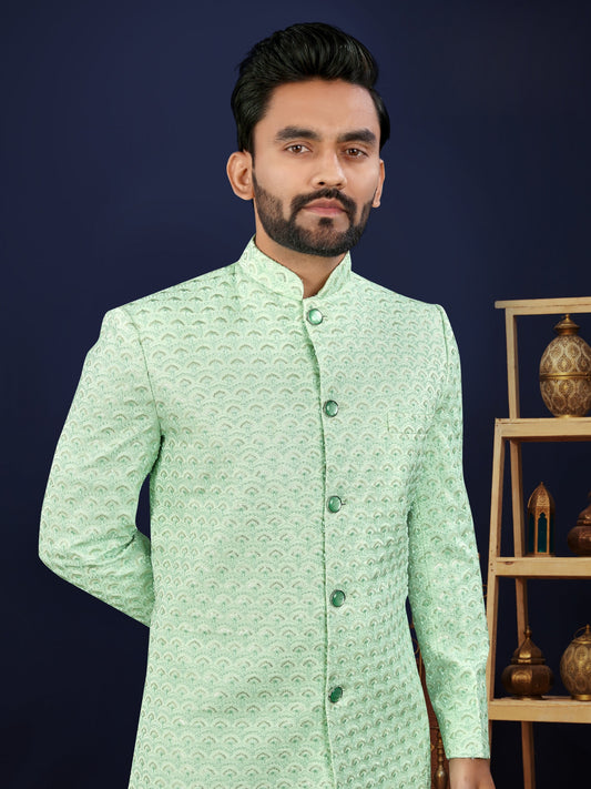 Man wearing a light green traditional jacket with a dark blue background