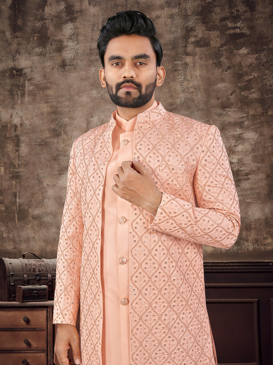 Man wearing a peach embroidered sherwani against a textured brown background
