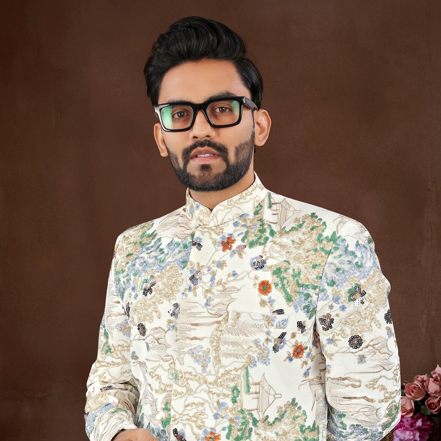Man wearing a floral embroidered sherwani against a brown background
