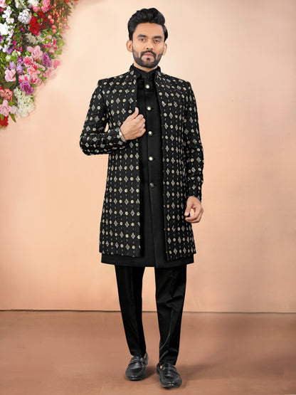 Man wearing a black and white patterned sherwani with a plain background