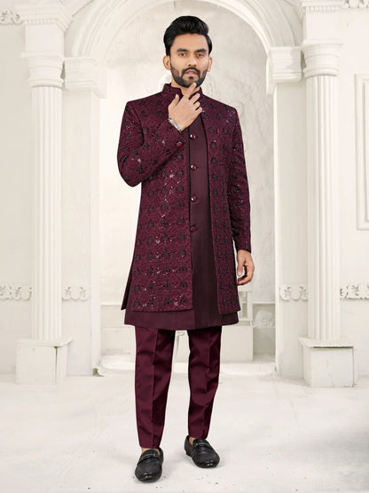 Man wearing a maroon traditional outfit with a white architectural background