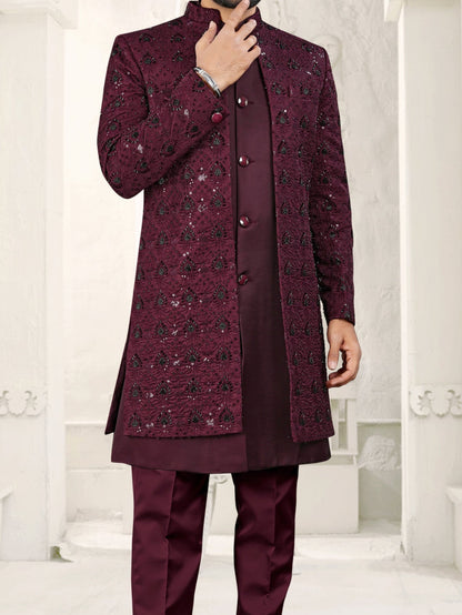 Man wearing a maroon traditional outfit with a white architectural background