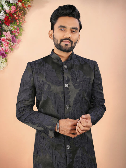 Man wearing a black traditional outfit with a floral background