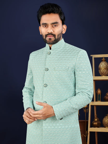 Man wearing a light blue traditional jacket against a dark background