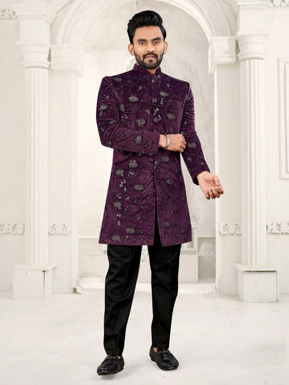 Man wearing a purple embroidered sherwani in a white architectural setting