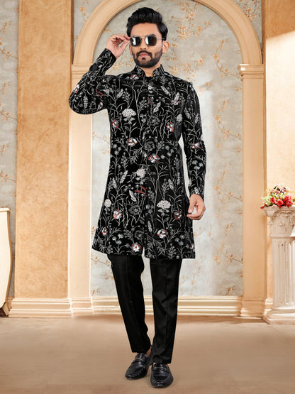 Man wearing a black floral sherwani in an elegant interior setting