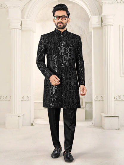 Man wearing a black embroidered sherwani in an elegant interior setting