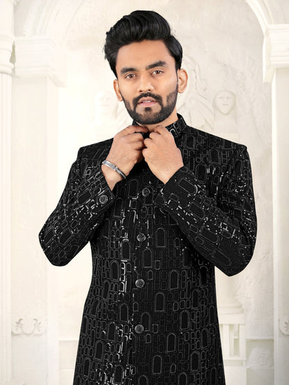 Man wearing a black embroidered sherwani against a white background