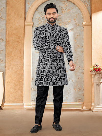 Man wearing a black and white patterned kurta with black pants in an ornate room.