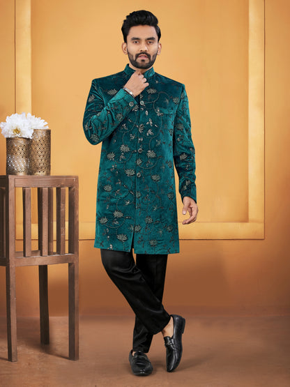 Man wearing a green embroidered sherwani against an orange background