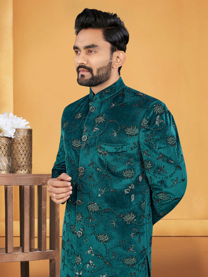 Man wearing a teal embroidered sherwani against an orange background