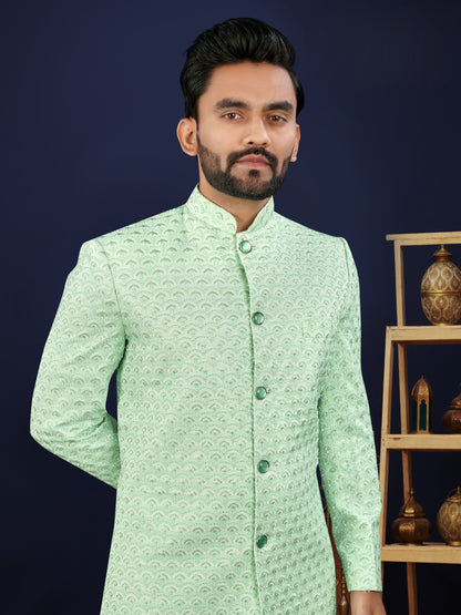 Man wearing a light green traditional jacket with a dark blue background