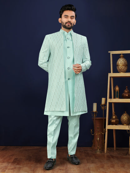 Man wearing a light green traditional outfit against a dark blue background