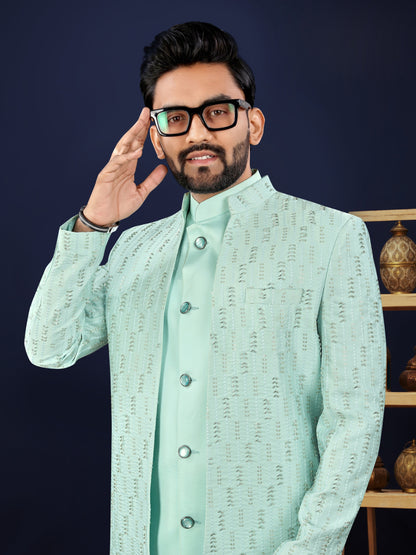 Man wearing a light green traditional outfit with a dark background