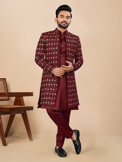 Man wearing a maroon traditional outfit with a beige background
