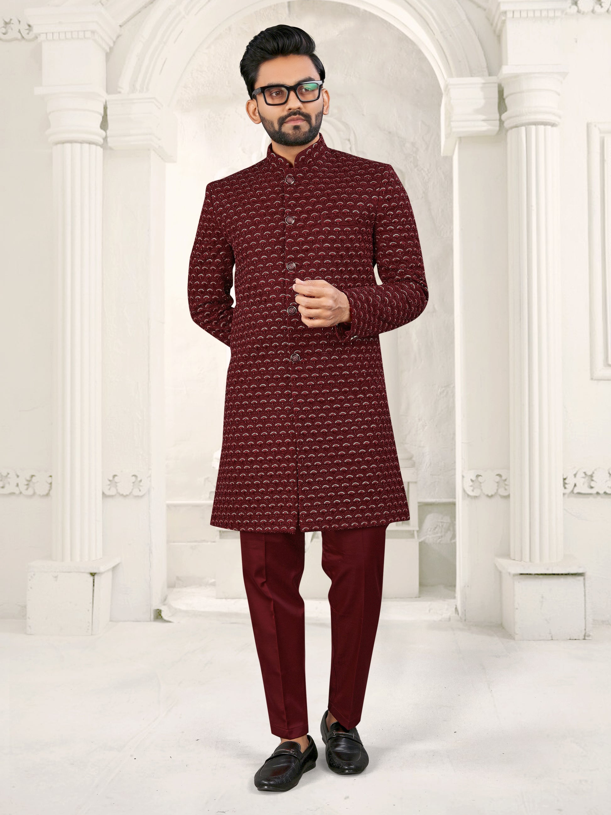 Man wearing a maroon traditional outfit with a white background