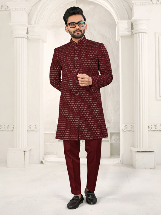 Man wearing a maroon traditional outfit with a white background