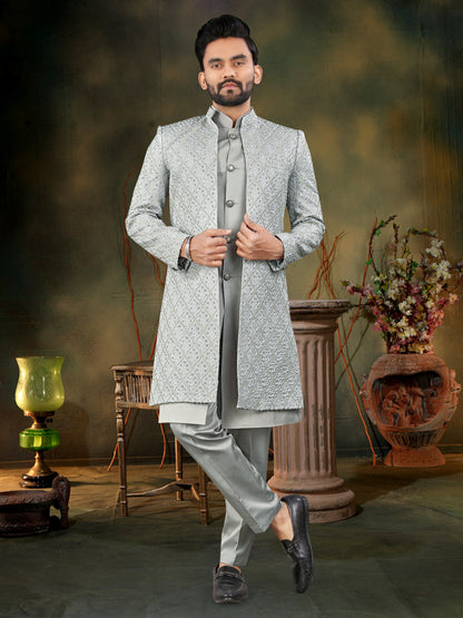 Man wearing a traditional gray sherwani in a decorated indoor setting.