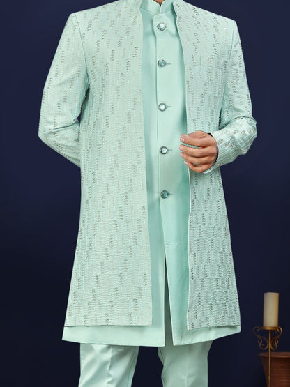 Man wearing a light green traditional outfit against a dark blue background