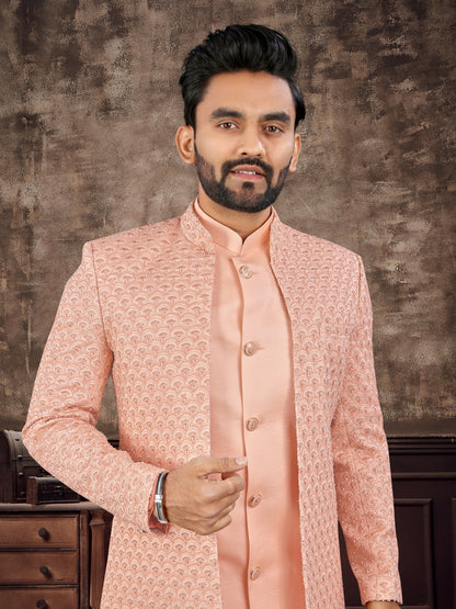 Man wearing a peach traditional outfit against a textured brown background