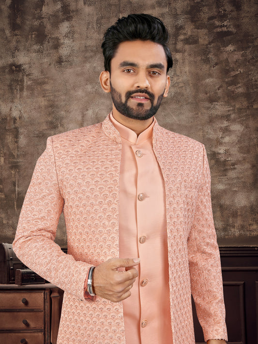 Man wearing a peach traditional outfit against a textured brown background